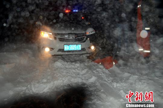 圖為消防人員跪在雪地里用鐵鍬鏟雪救援被困車輛。　李江江　攝